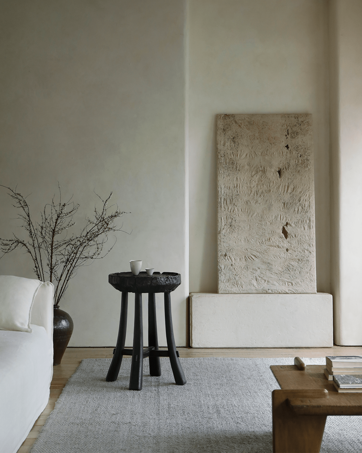 Basin Side Table in a modern living room setting, dark wooden stool with carved top
