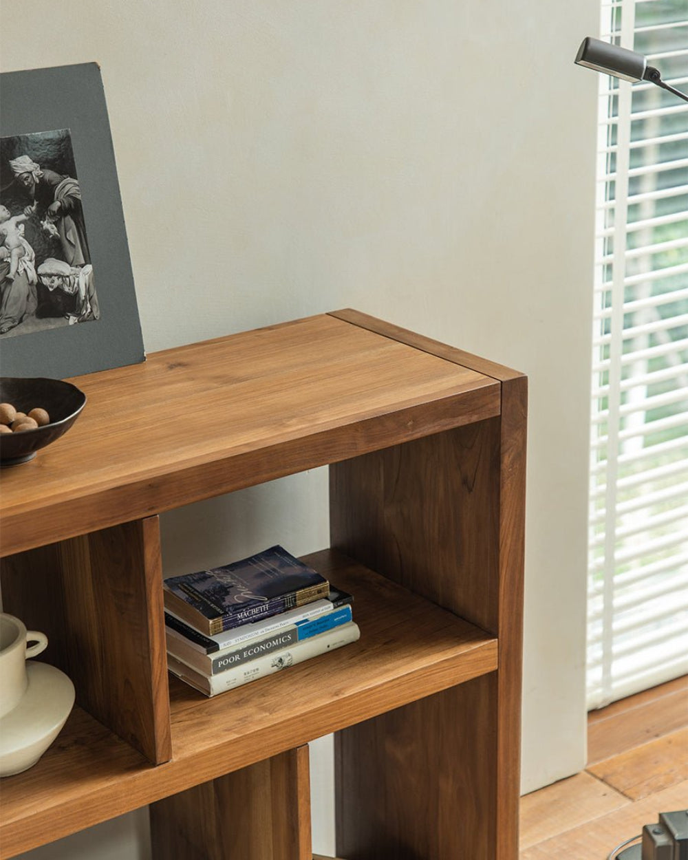 Teak Tome Bookcase with 'MACHETT', 'POOR ECONOMICS' books, art, decor.