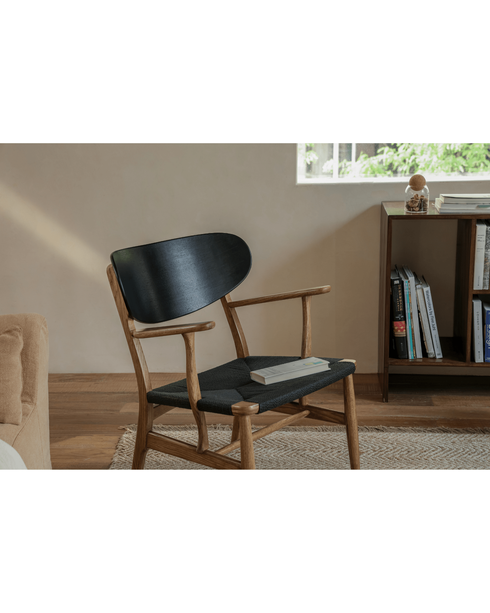 CH22 Lounge Chair with black backrest, oak frame, and paper cord seat in modern interior.