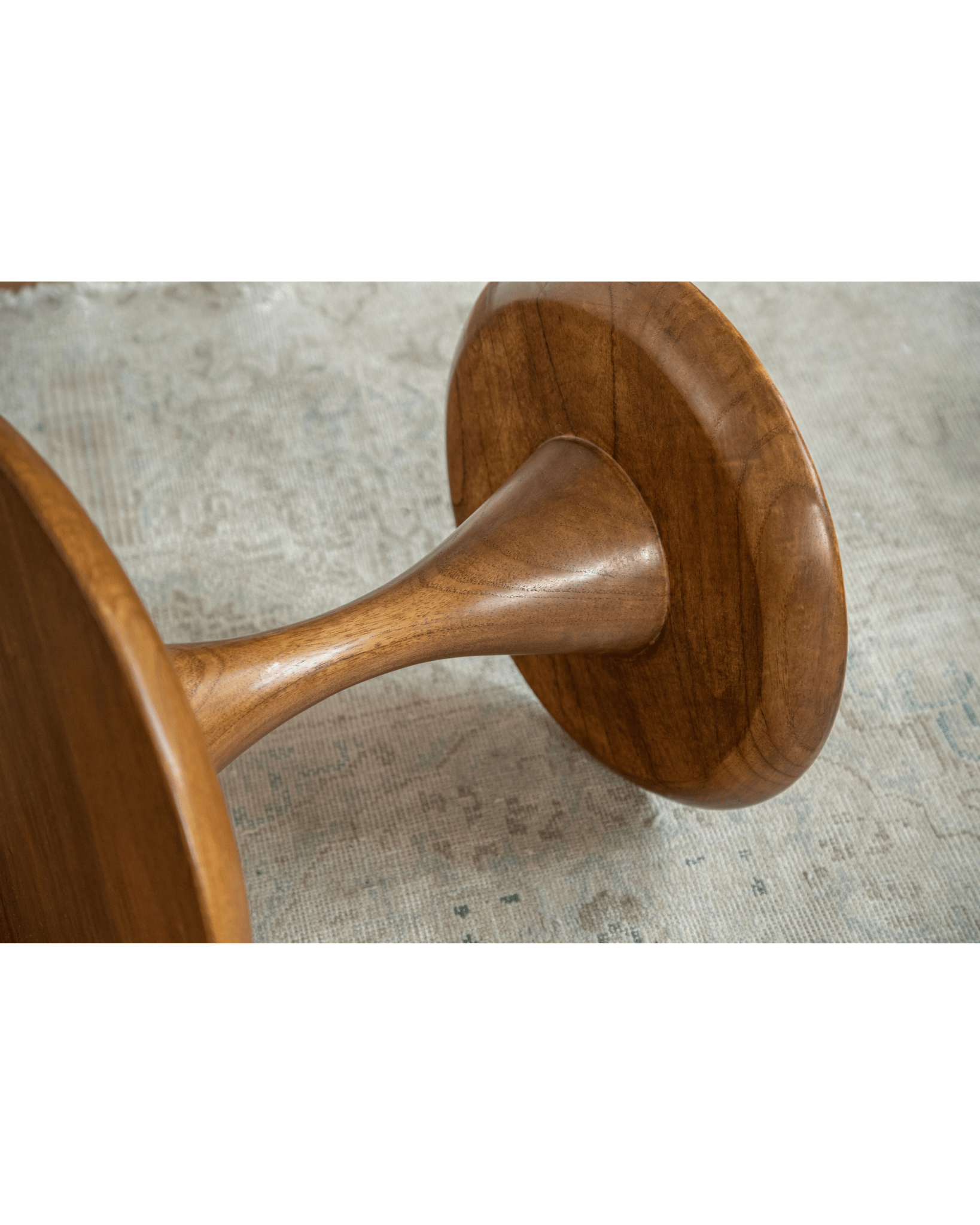 Close-up of Spindle Side Table's solid teak hourglass base, showing rounded edges and elegant design.