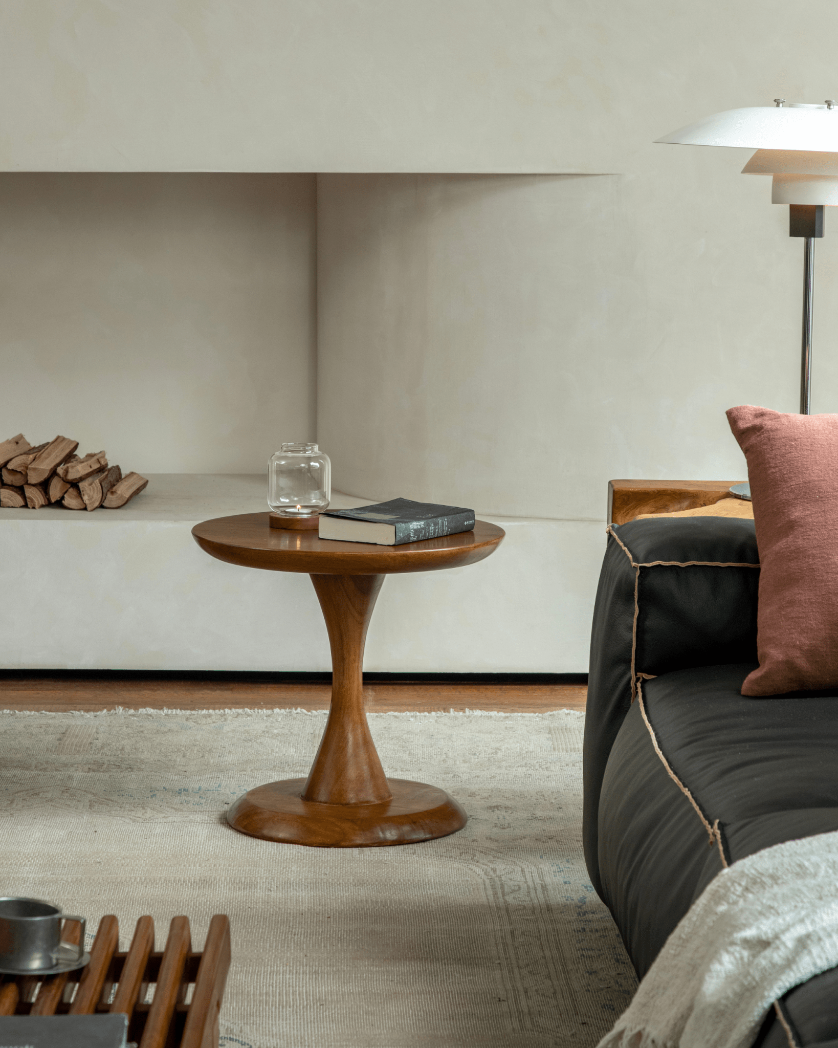 Spindle Side Table in solid teak, with hourglass base. Elegant side table in a living room setting with book and decor items.