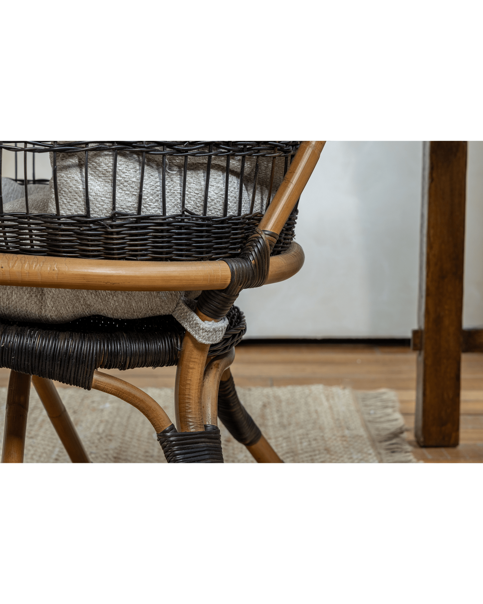 Helian Rattan Chair detail: natural rattan frame with black accents and gray cushion, handcrafted design