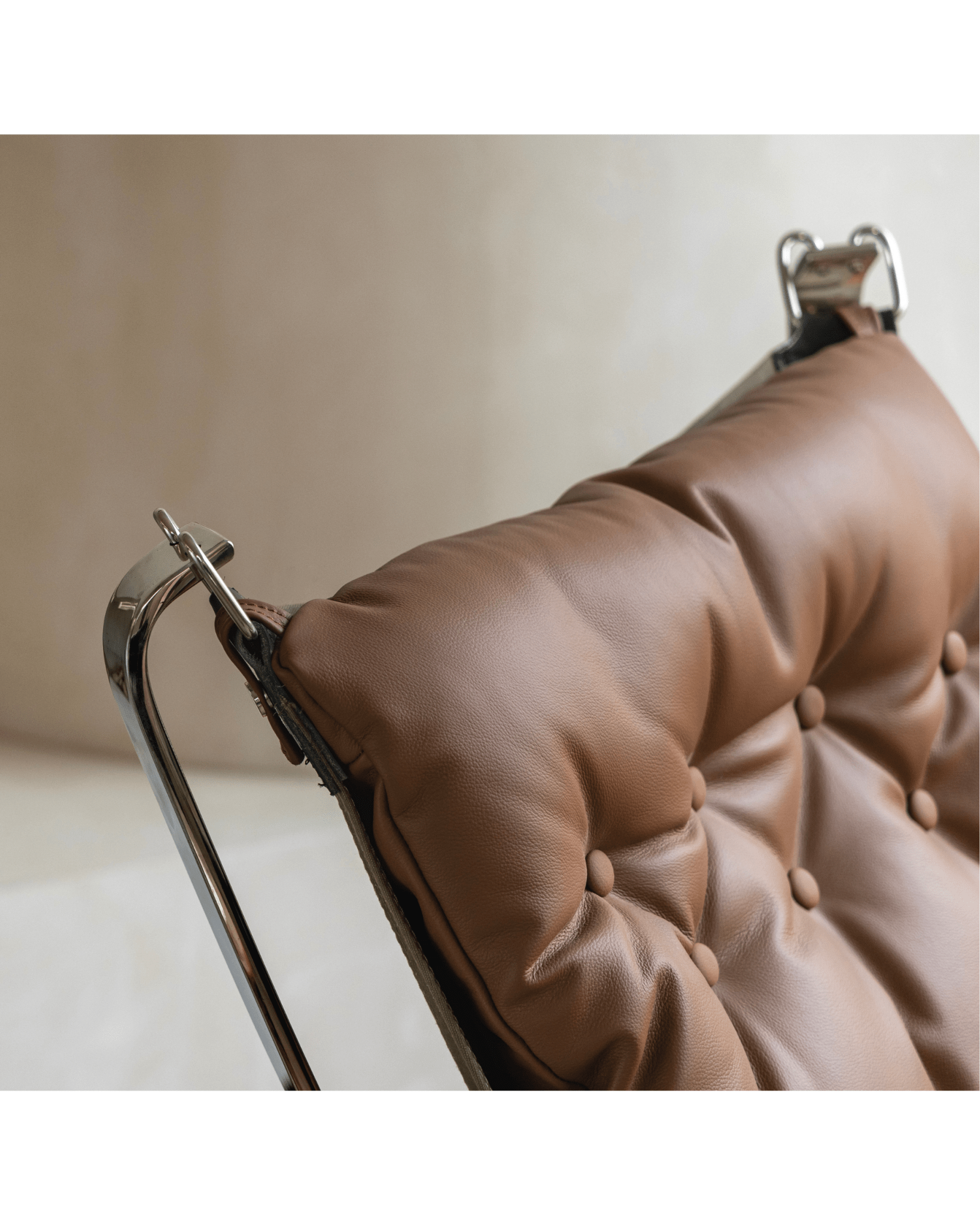 Brown leather Falcon Chair cushion detail with stainless steel frame, Scandinavian design