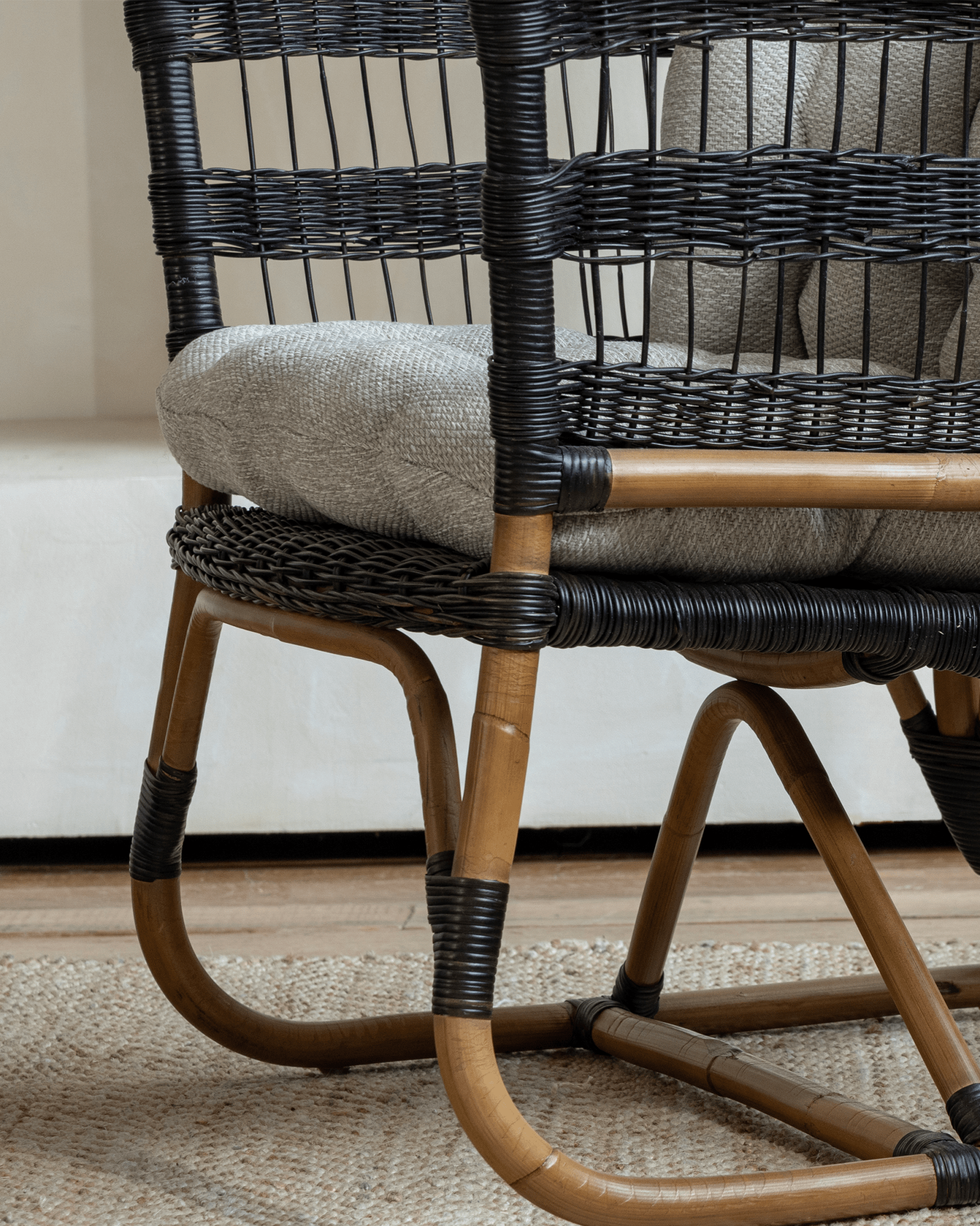 Helian Rattan Chair, black rattan accents, gray cushion, and natural frame, stylish and cozy interior design.