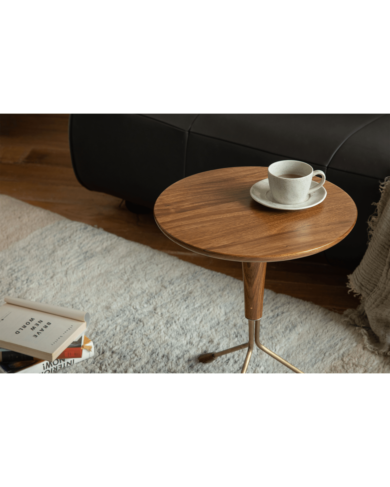Larsson Side Table with ebony wood top, brass base and tea cup. Modern living room.