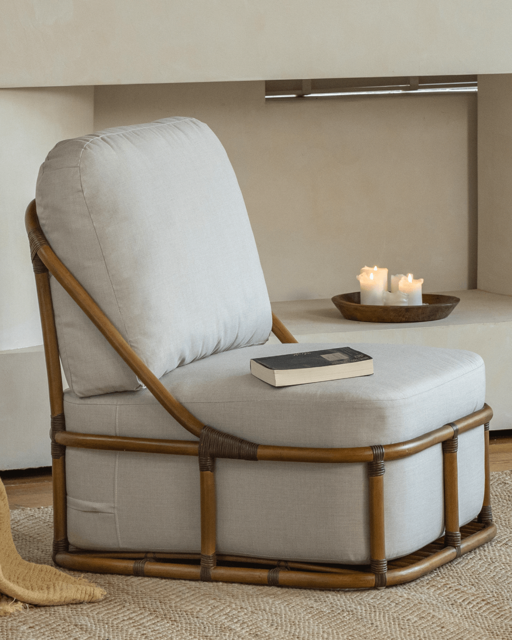 Tofu Lounge Sofa with rattan frame, light gray cushion and a book on the seat, comfortable seating.