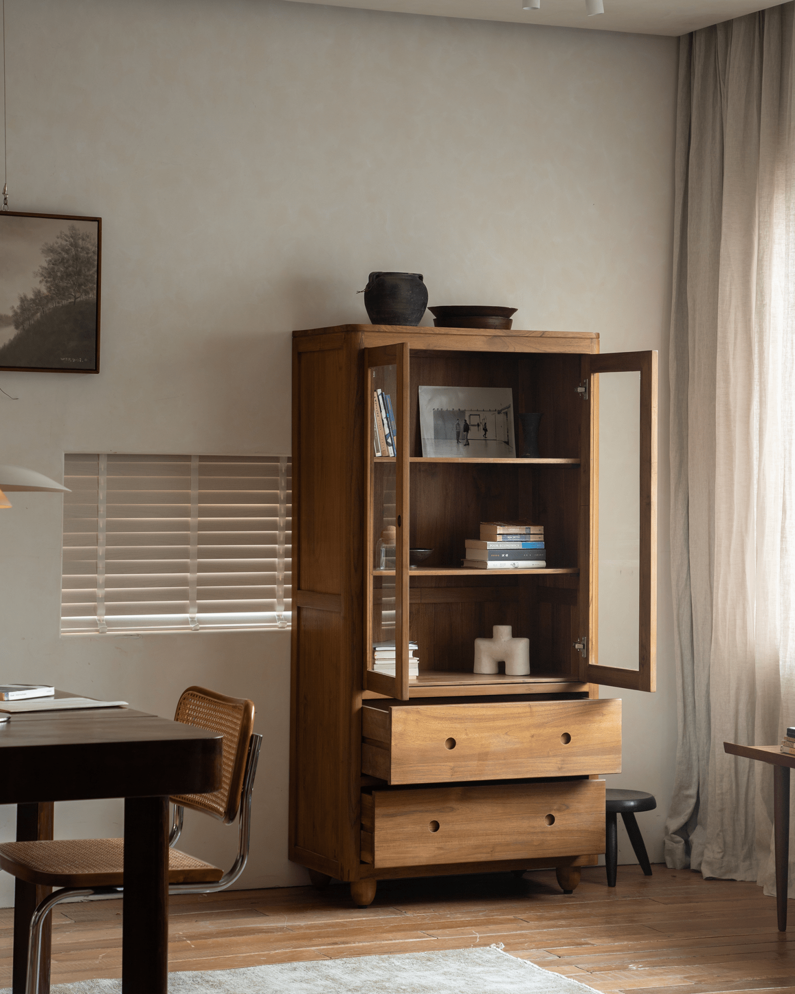 Reve Teak Bookcase in a living room. Teak wood bookcase with double glass doors and drawers for spacious storage