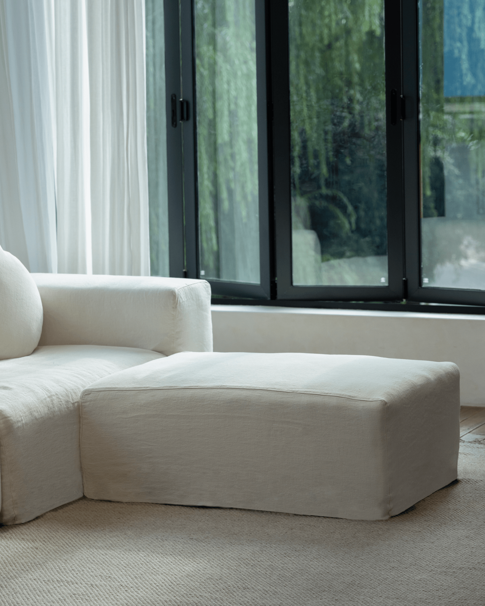 Doma Sectional Sofa in white linen, wide armrests and ottoman, bright living room