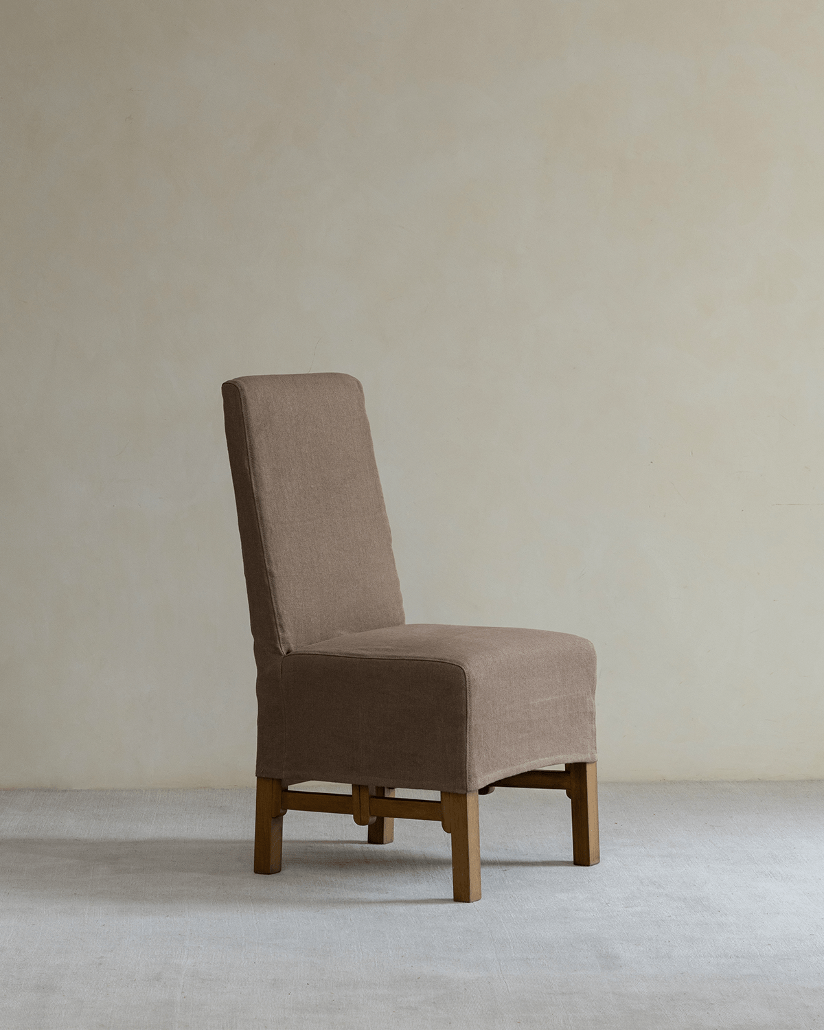 Feast Dining Chair with brown linen slipcover, wooden frame, modern design, neutral tones.