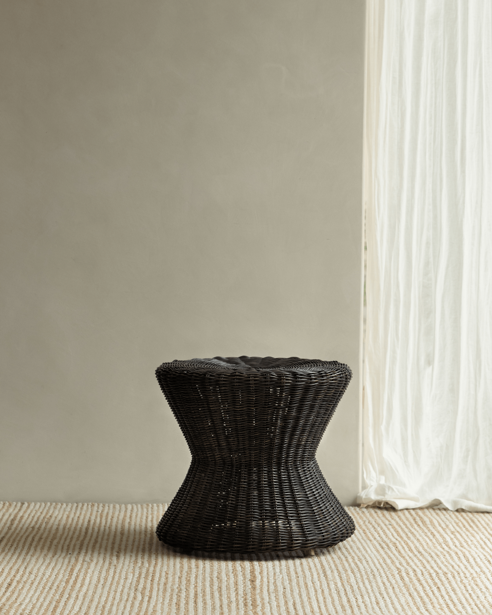 Black Bongo Rattan Side Table with hourglass shape and spiral rattan weave.