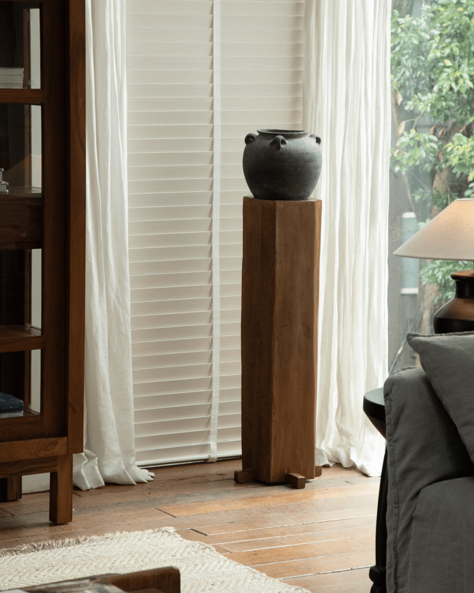 Rustic wooden pedestal with dark vase, organic interior design, natural aged wood, timeless simplicity