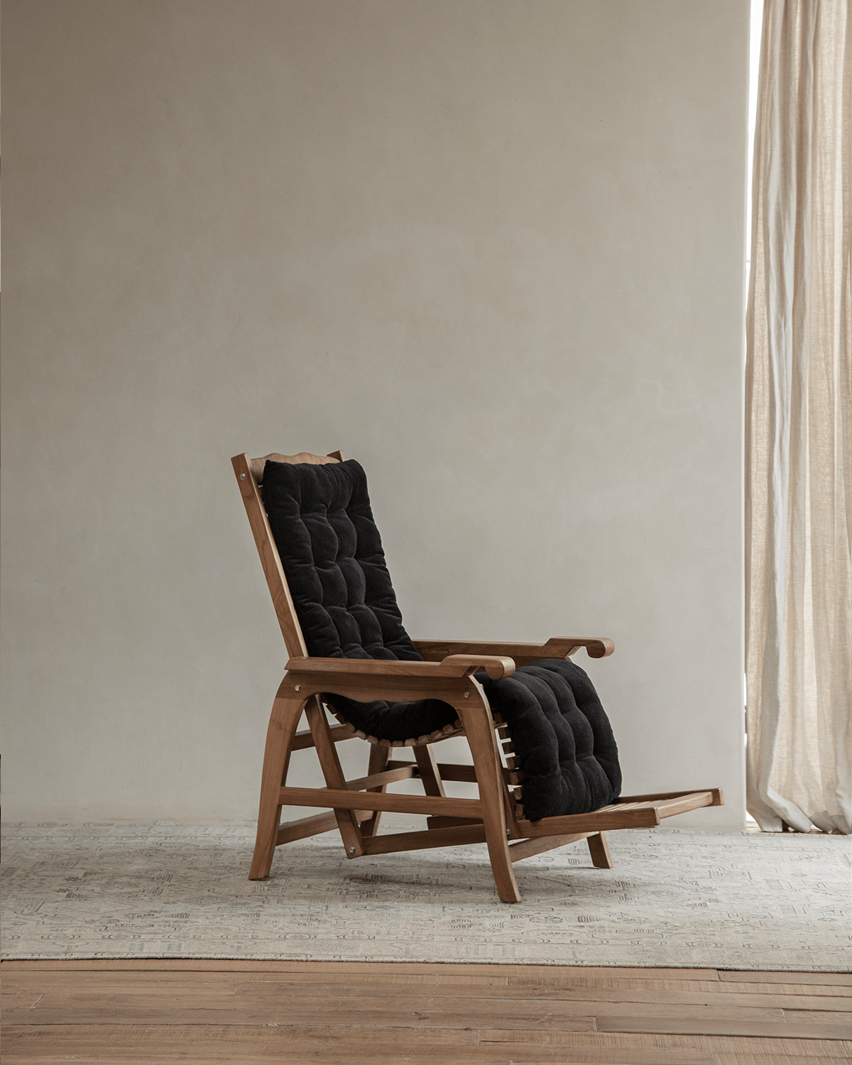 Teak Roller Chaise Lounge Chair with black cushion in a modern living room setting for relaxation