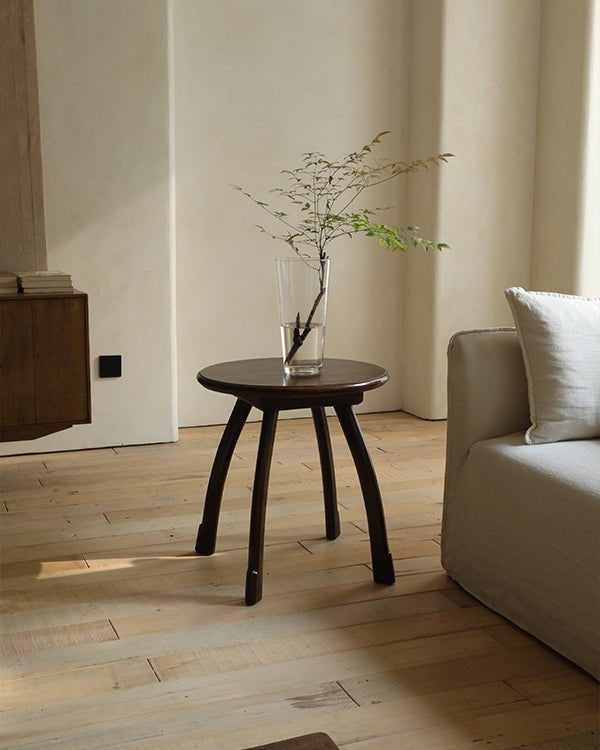 Ele Round Side Table with dark Phoebe wood, octopus legs, and vintage finish in a cozy interior setting