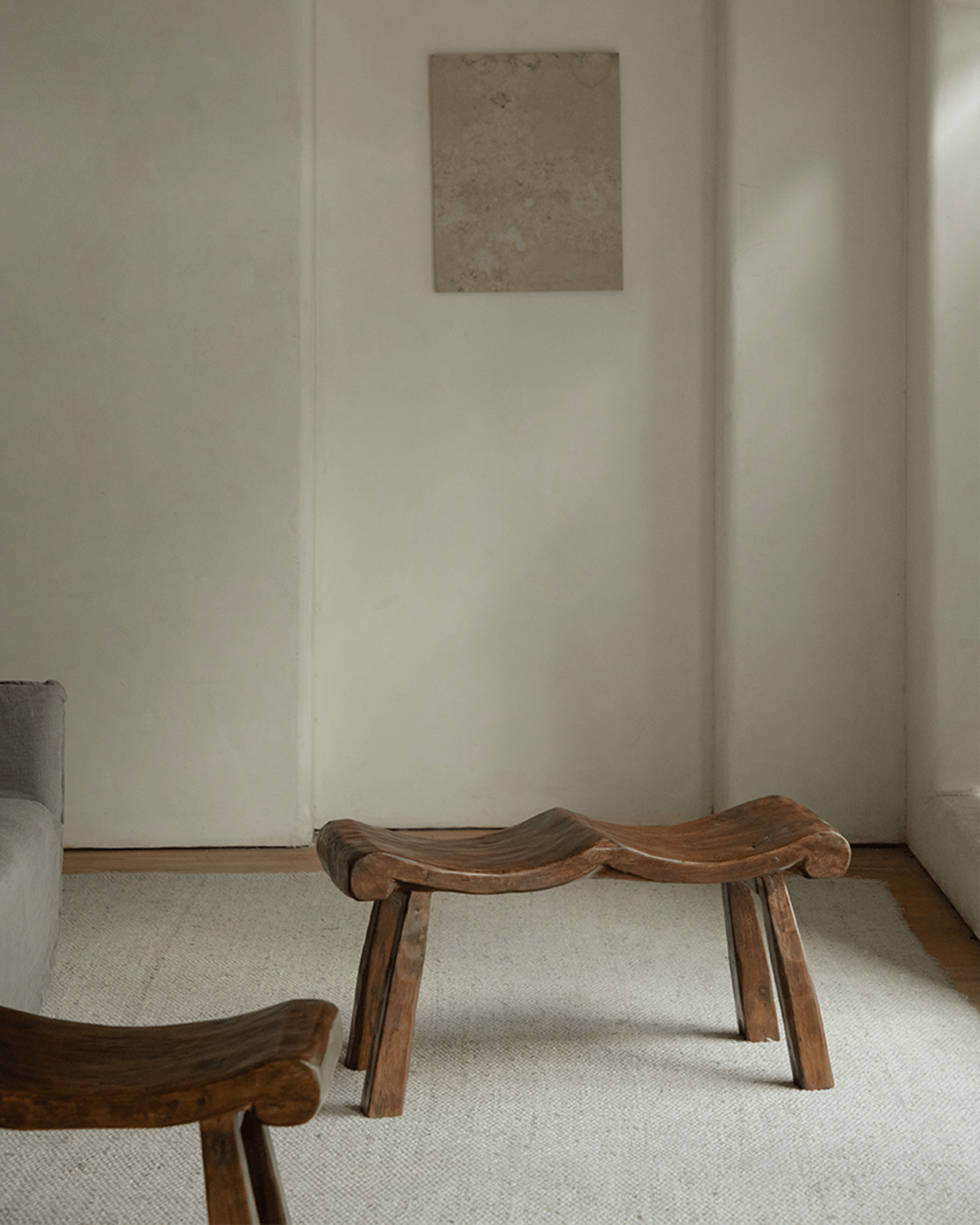 Tildes Bench in a minimalist interior setting. Solid wood bench with curved seat and sturdy legs, brown color.