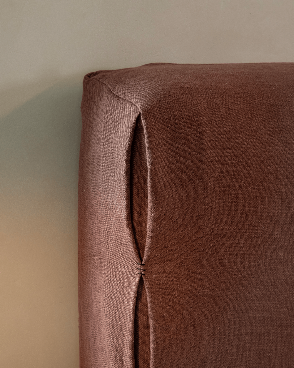 Freya Linen Bed headboard detail in terracotta linen, showcasing stitching and texture, perfect for peaceful sleep.