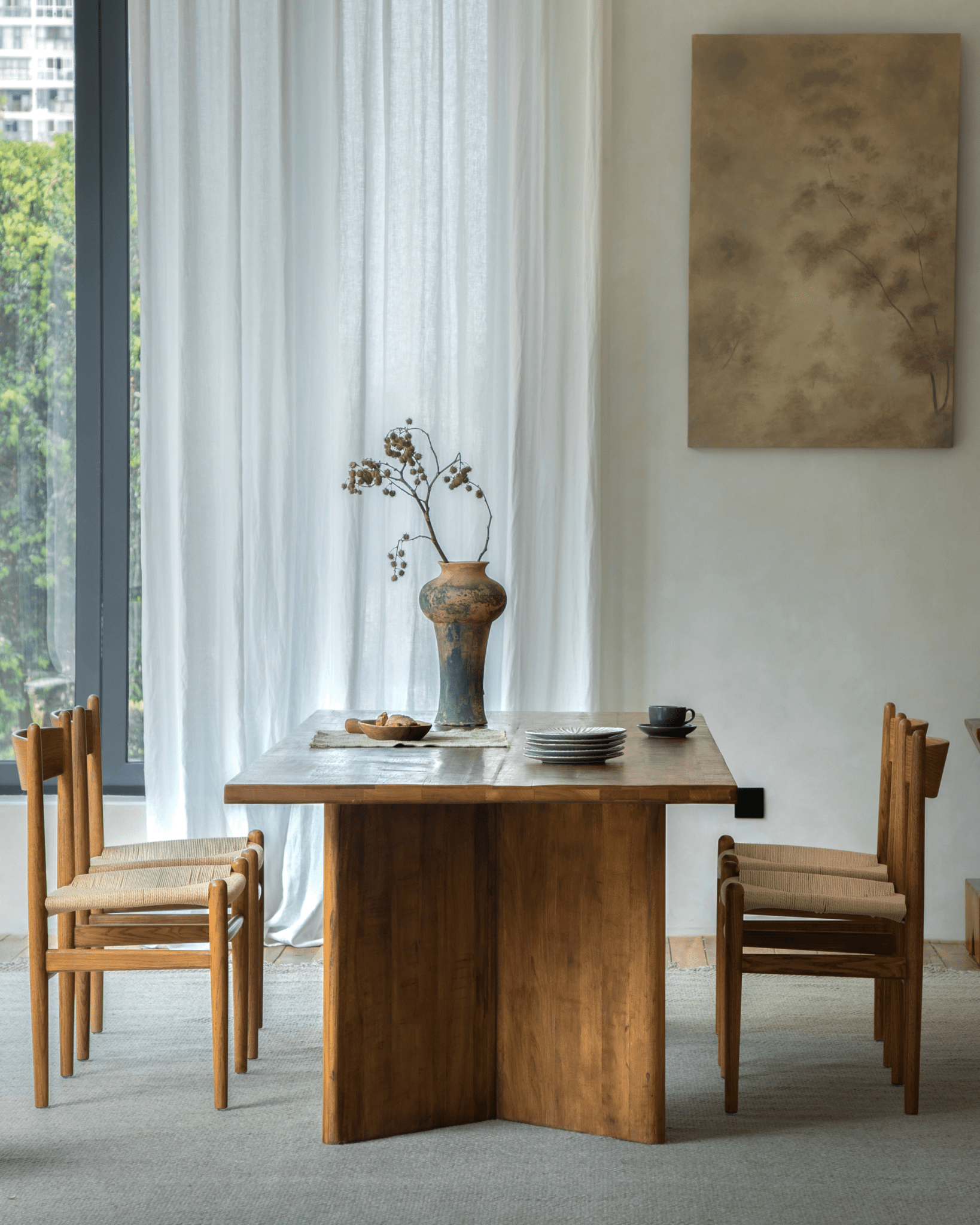 Zephyr Dining Table styled with matching chairs, vase, and decor. Reclaimed wood dining table with folded leg design.