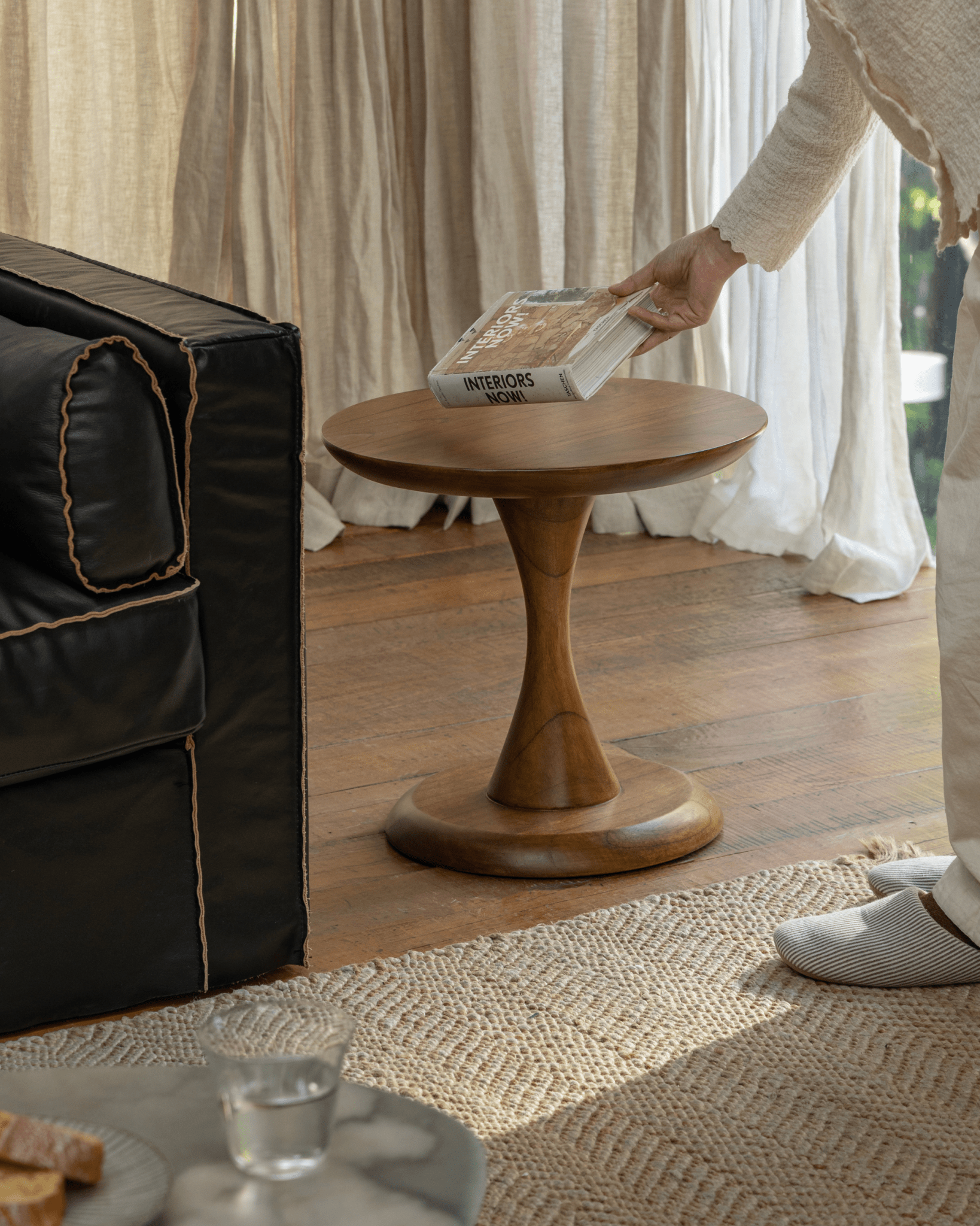 Solid teak Spindle Side Table with a book "INTERIORS NOW!" and hourglass base, perfect for living room decor.