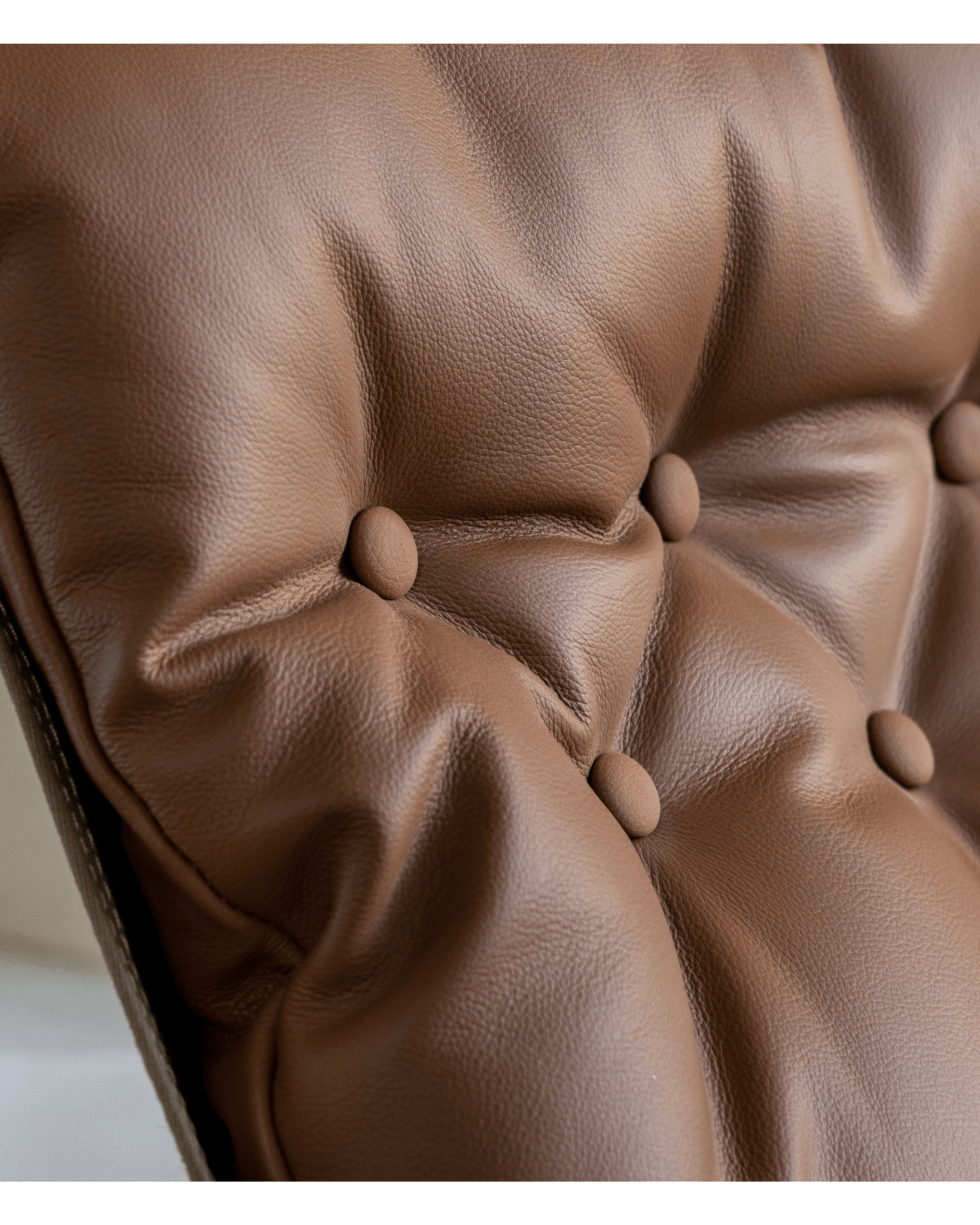 Close-up of brown leather Falcon Chair cushion with button tufting, Scandinavian design, premium comfort