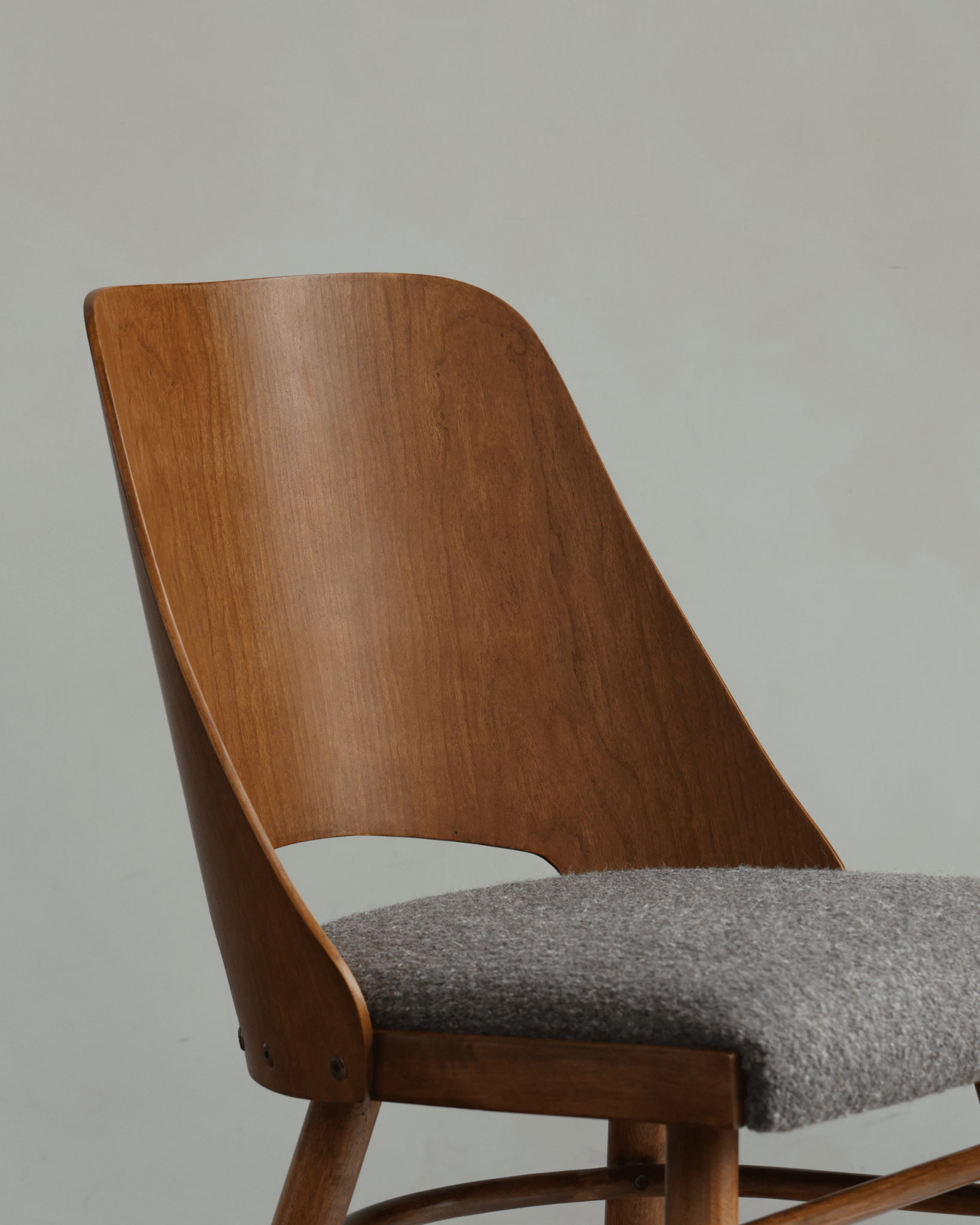 Shell Chair close-up: Teak wood backrest and grey loop fabric seat, mid-century modern design