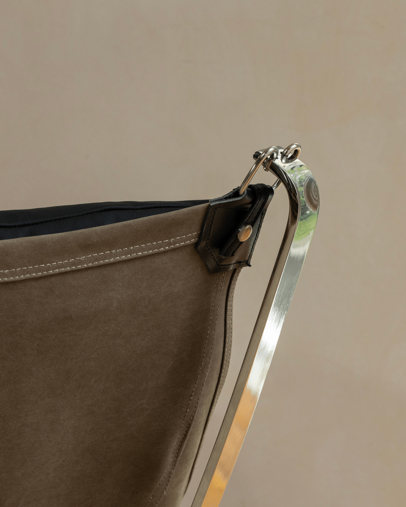 Falcon Chair detail: olive green canvas, black leather accent, and stainless steel frame, Scandinavian design