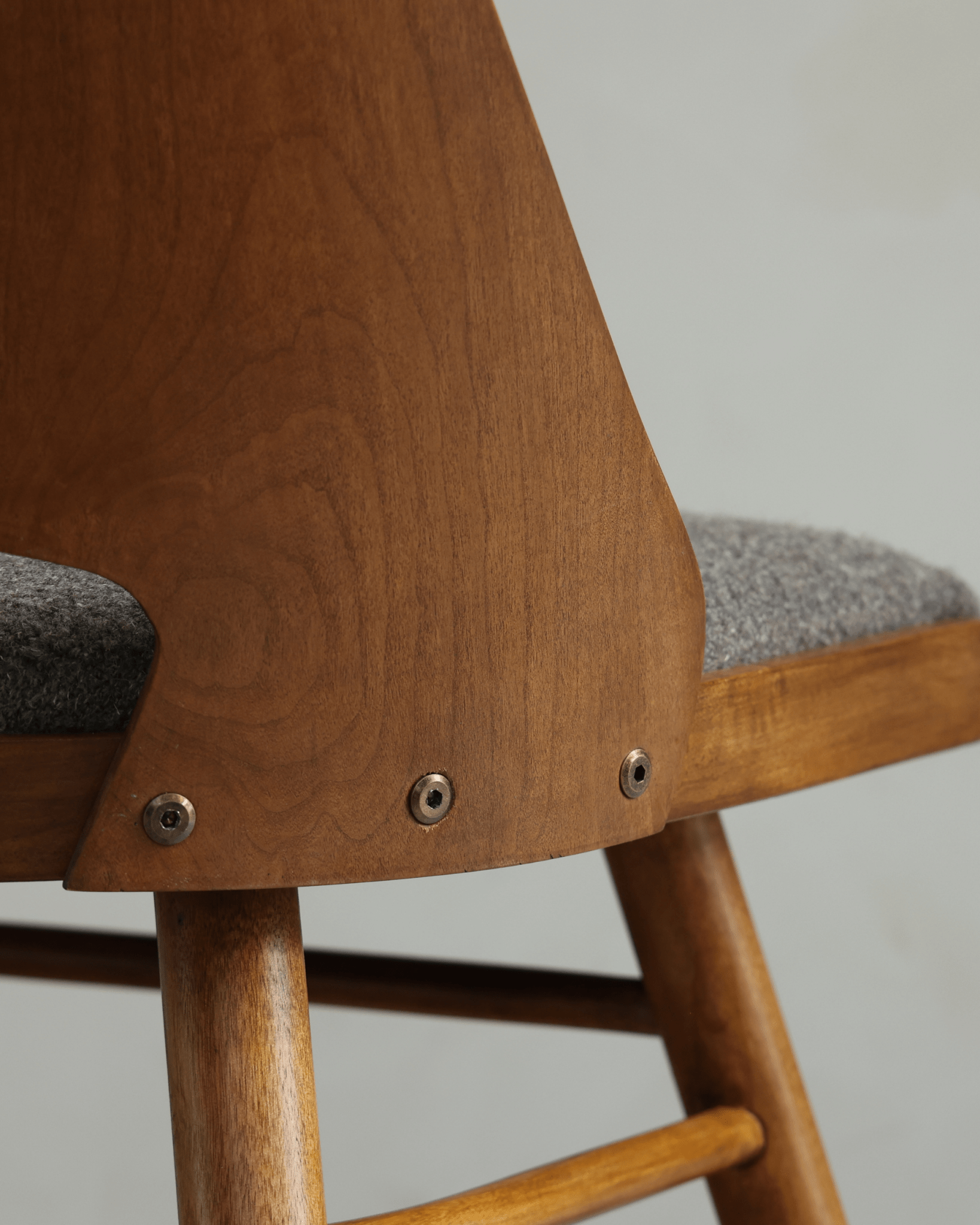 Shell Chair close-up: Teak wood backrest with grey loop fabric seat, mid-century modern design