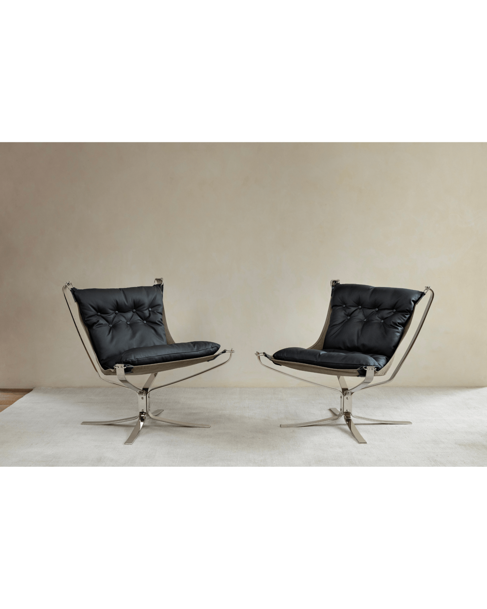 Pair of black leather Falcon Chairs, Scandinavian design, stainless steel frame, modern living room.