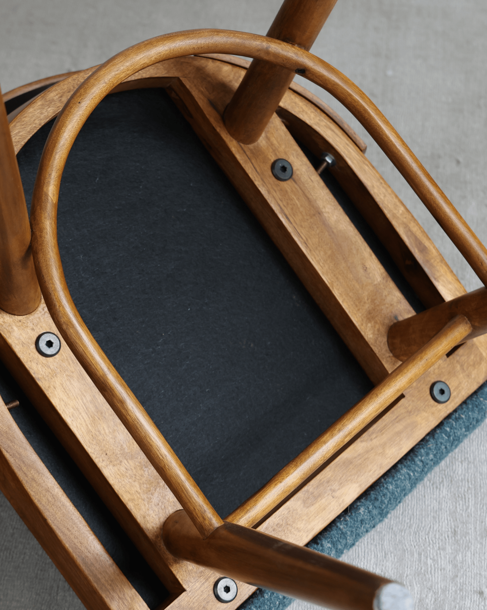 Shell Chair underside detail: solid teak frame, curved legs, and blue fabric seat, mid-century modern design