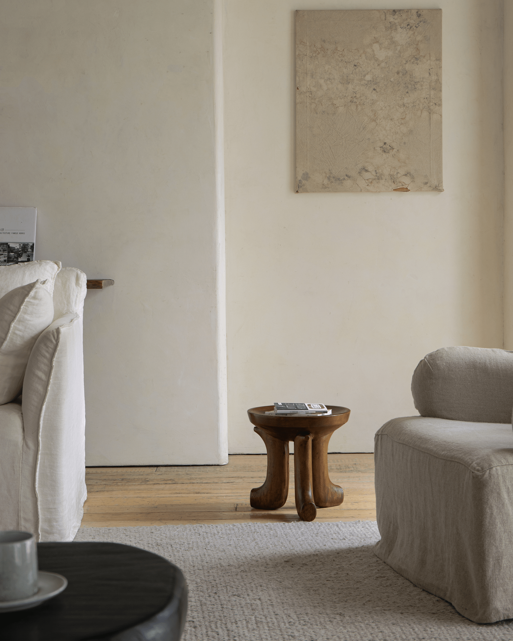 Quincy Stool in cozy living room setting, three-legged design, solid wood, showcasing modern home decor.