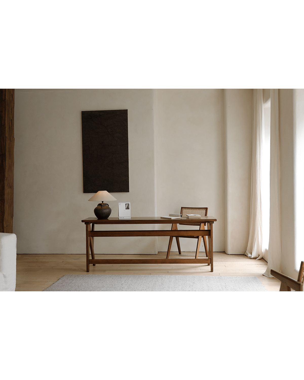 Teak writing desk in home office with lamp, chair, rug and calendar, showcasing wood grain.
