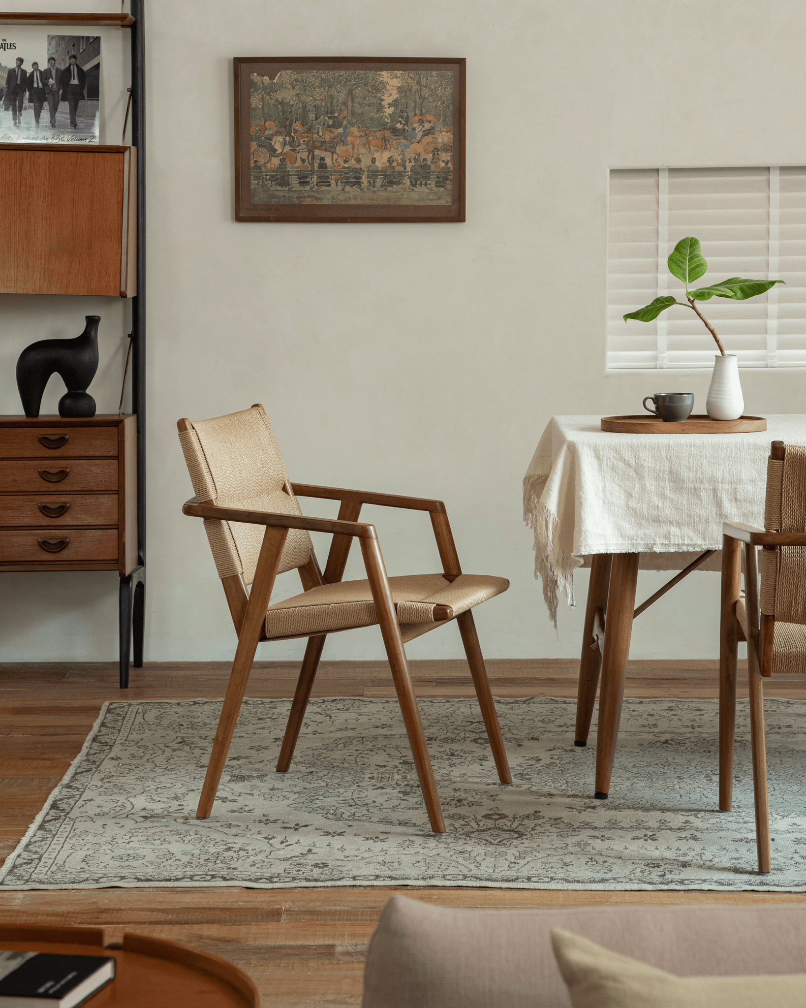 Luisa Chair in a dining room setting, showcasing teak frame, woven seat, and Mid-Century Modern design.