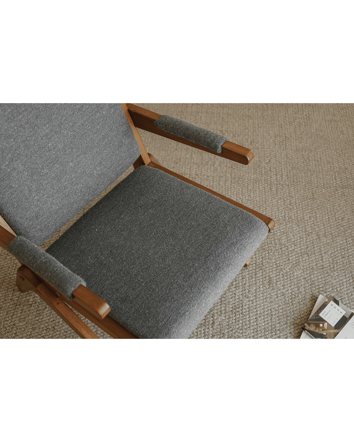 Scissors Chair in red oak with grey fabric, close-up view of the seat and armrest, modern design.