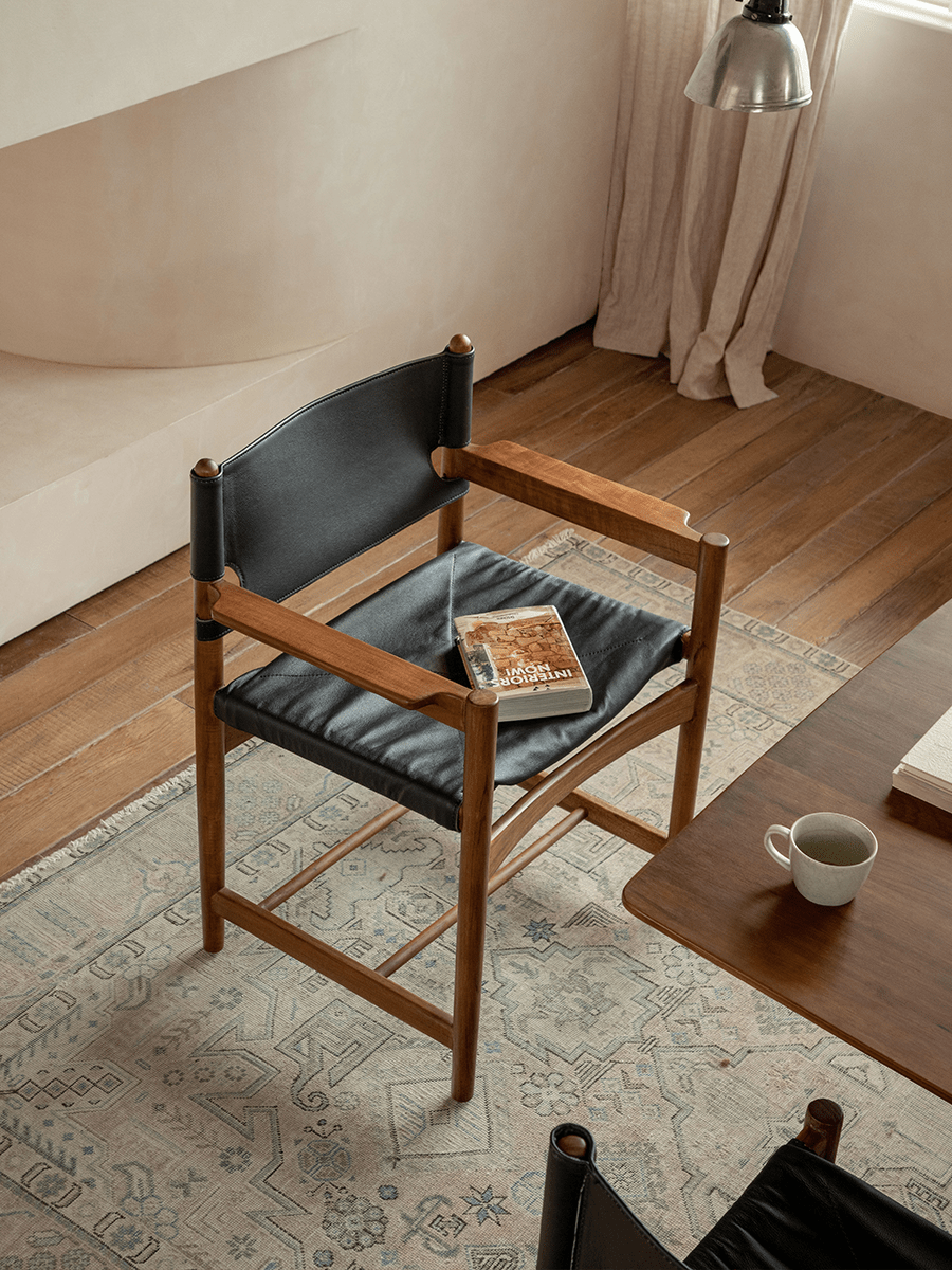 Spanish Dining Chair: Black leather and teak wood chair with interiors book in neutral dining room setting