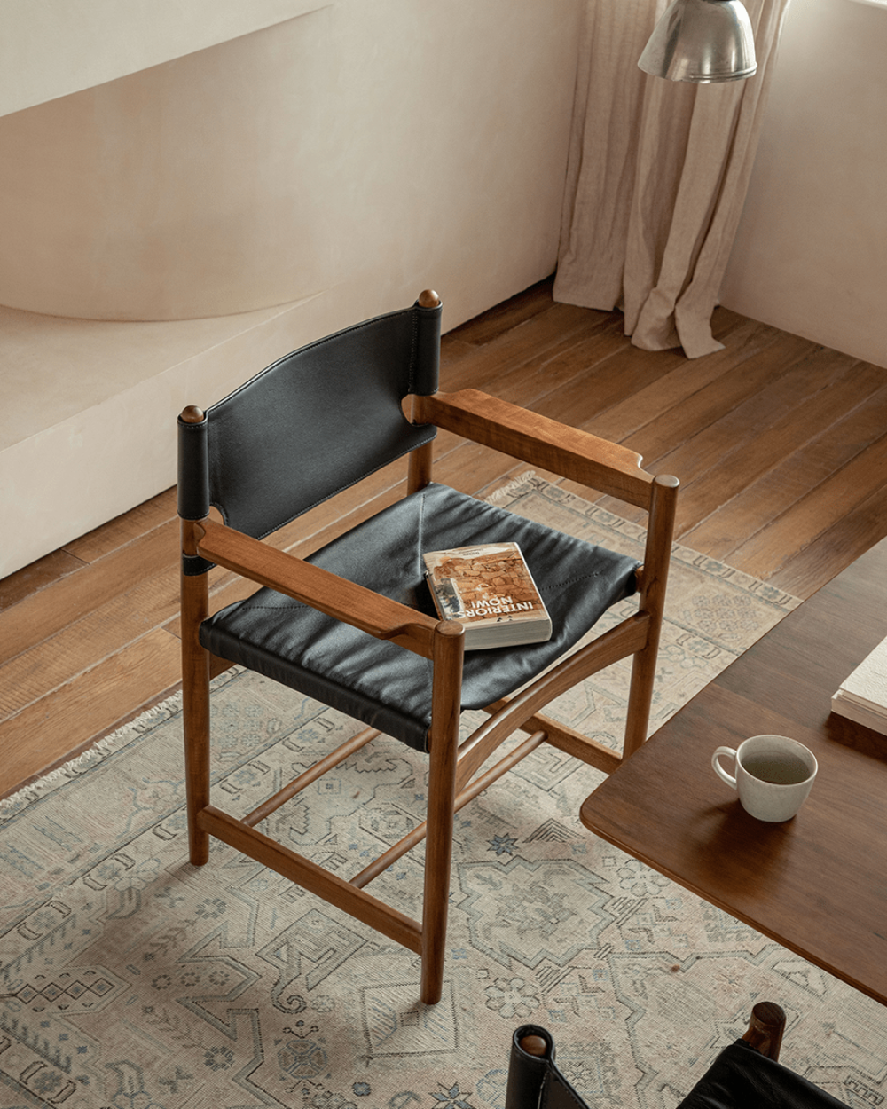 Spanish Dining Chair: Black leather and teak wood chair with interiors book in neutral dining room setting