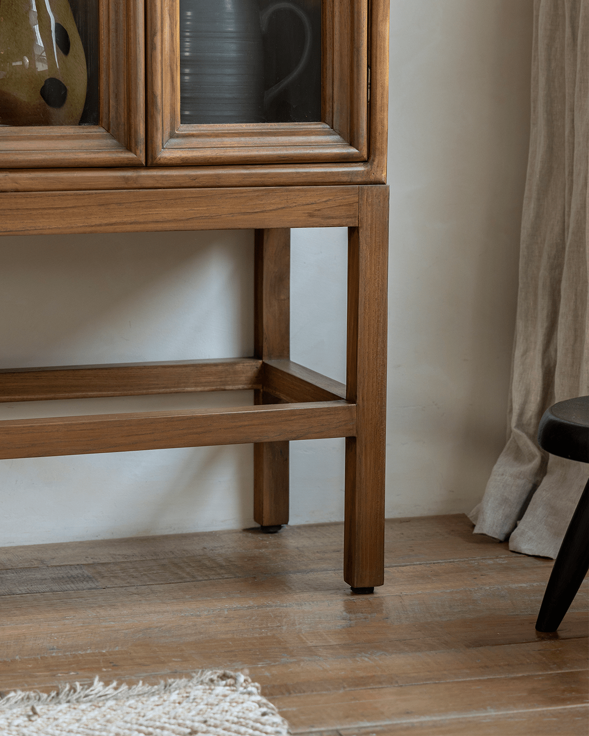 Teak Stilt Cabinet detail with glass doors, showcasing elegant teak wood grain and storage solution.