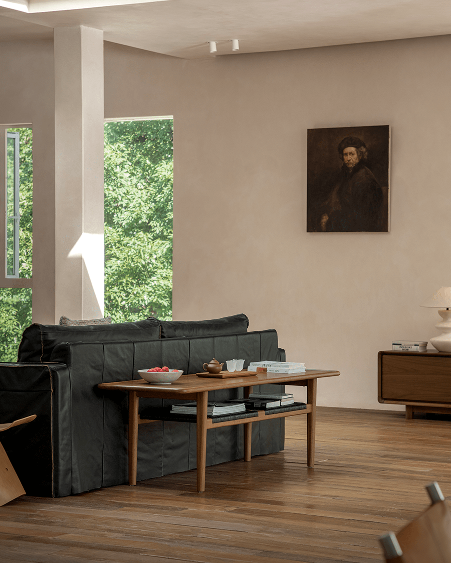 Hans Accent Table in modern living room setting, wooden table with dark books on the shelf, with black sofa.