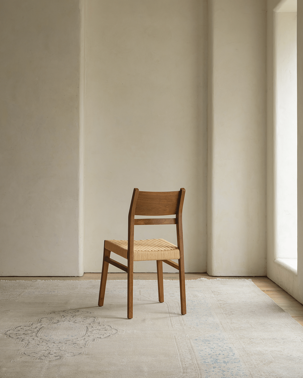 Beam Chair with teak wood frame and woven seat, showcasing design and natural warmth in elegant setting.