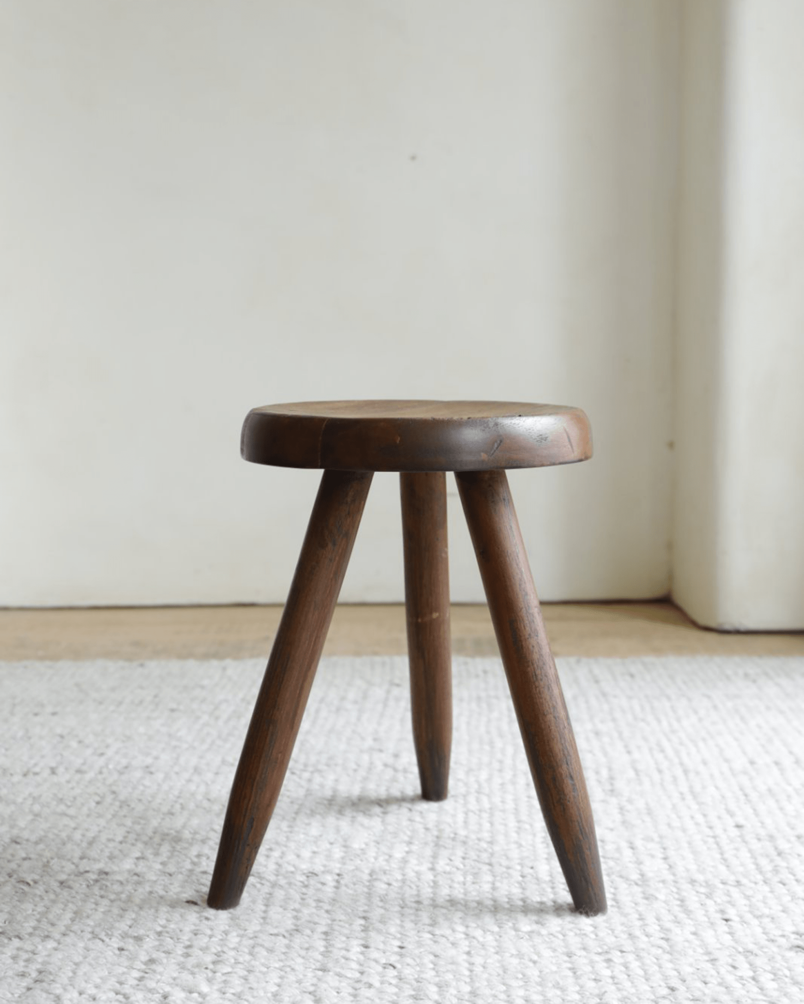 French stool in natural wood finish with round seat and three legs, perfect for modern home decor