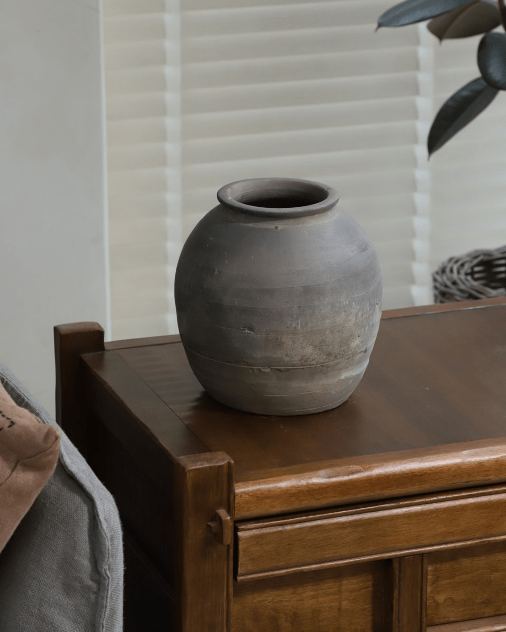Vintage clay pot, gray finish, on wooden table. Clay pot for home decor.