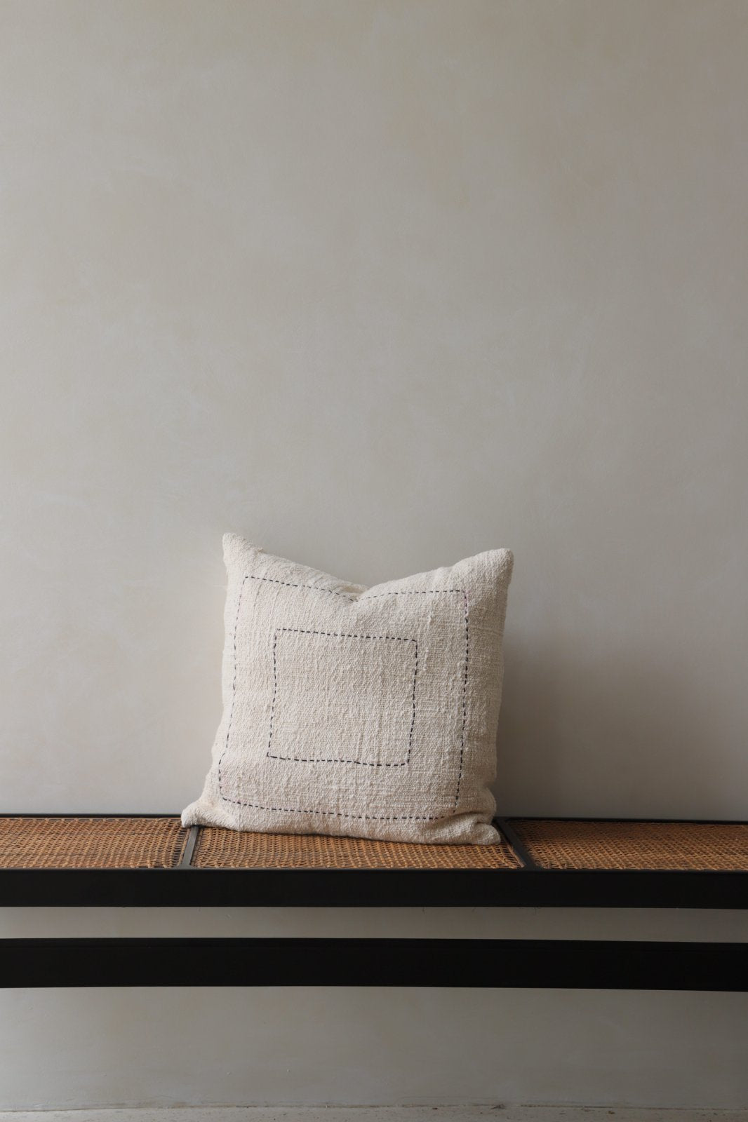 Cotton pillow with stitched square design, neutral color, on bench