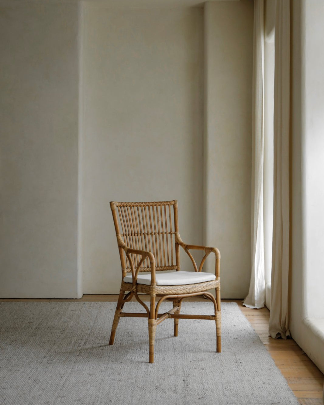 Axis Chair - Indonesian rattan armchair with white cushion in a neutral-toned interior