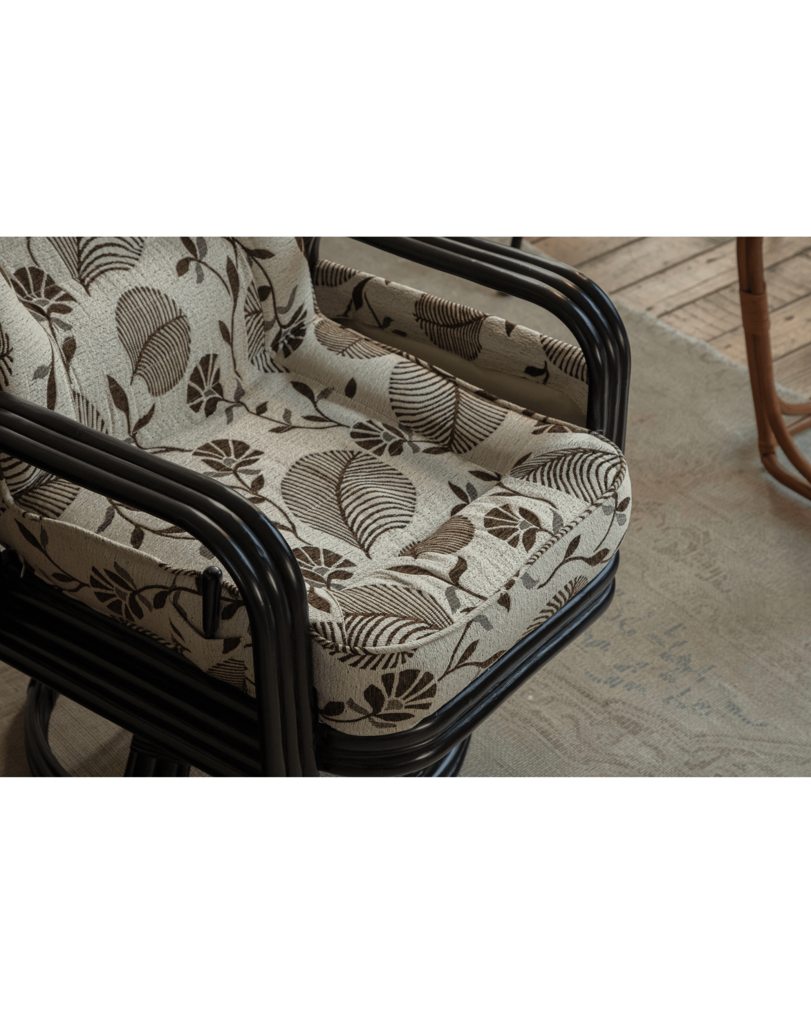 Willow Rattan Chair with floral leaf cushion and black rattan frame, for modern comfort