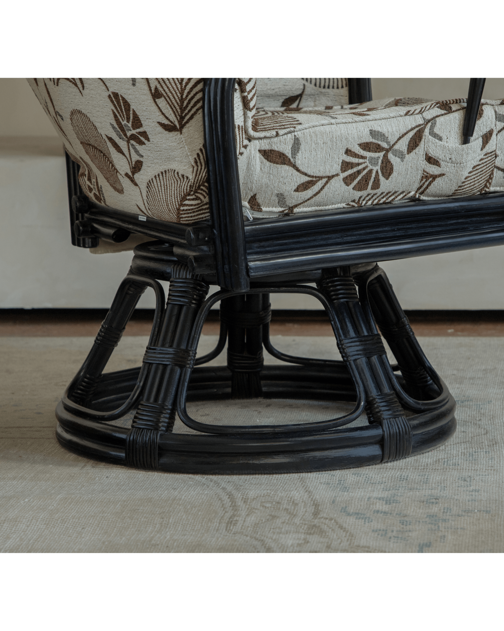 Close-up of Willow rattan chair base, black frame with floral cushion, Indonesian rattan for modern comfort