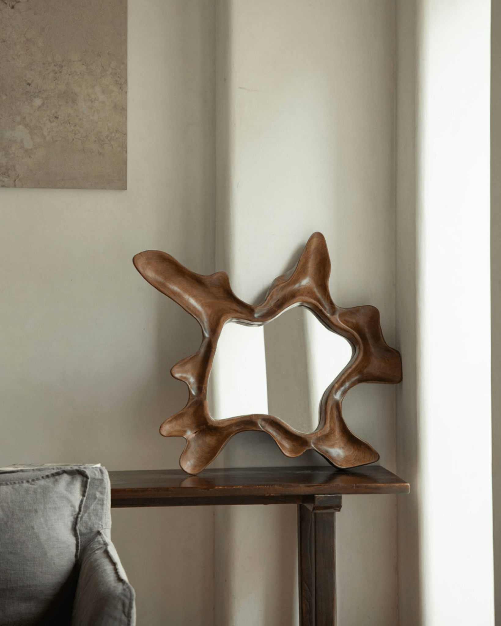 Organic Wood Arbor Mirror on dark wood table, modern wall decor for interior design, natural shape.