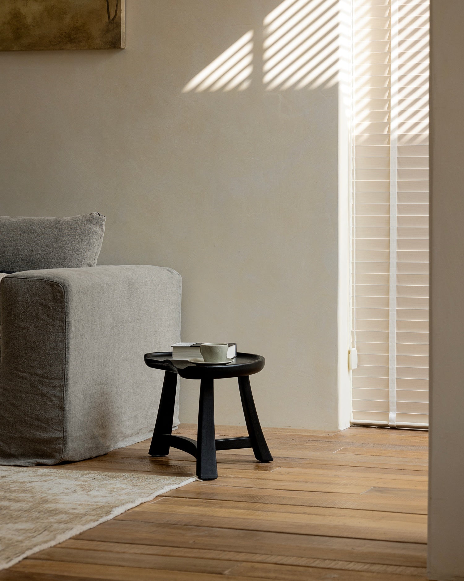 Black teak wood Pod Stool used as side table with books and cup.