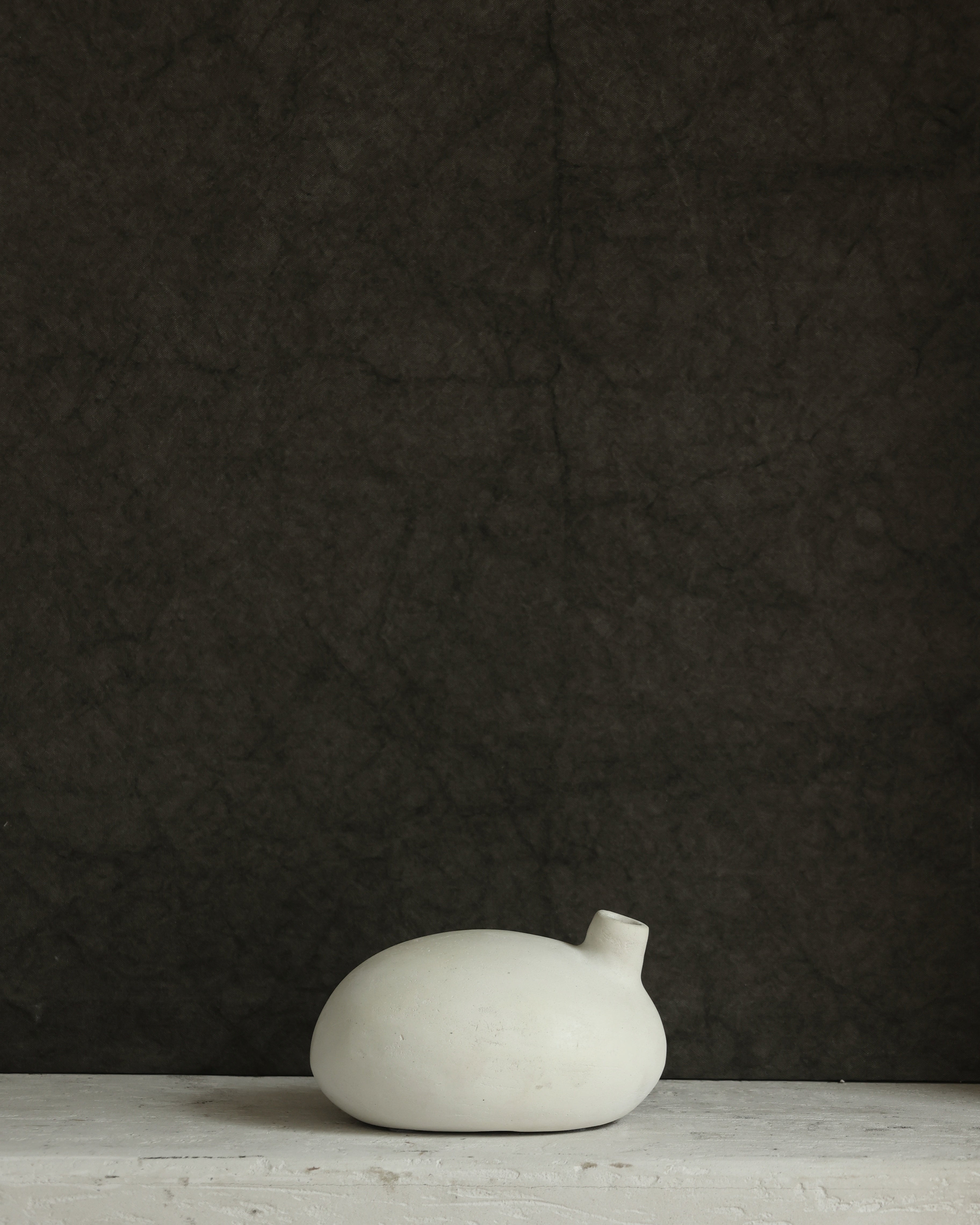 White ceramic object on a dark textured background