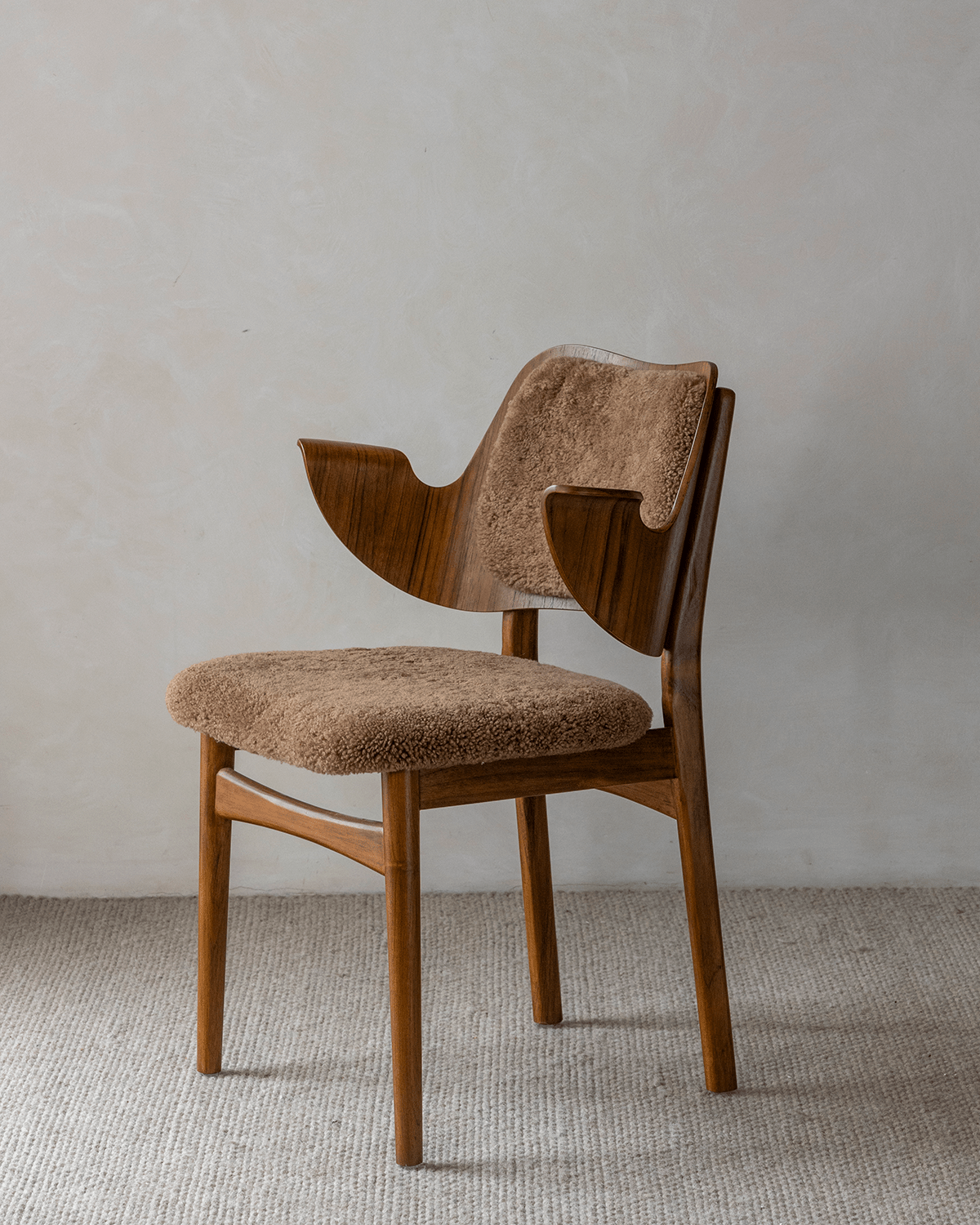 Maren Chair: Curved wood frame with beige lambswool seat and backrest.