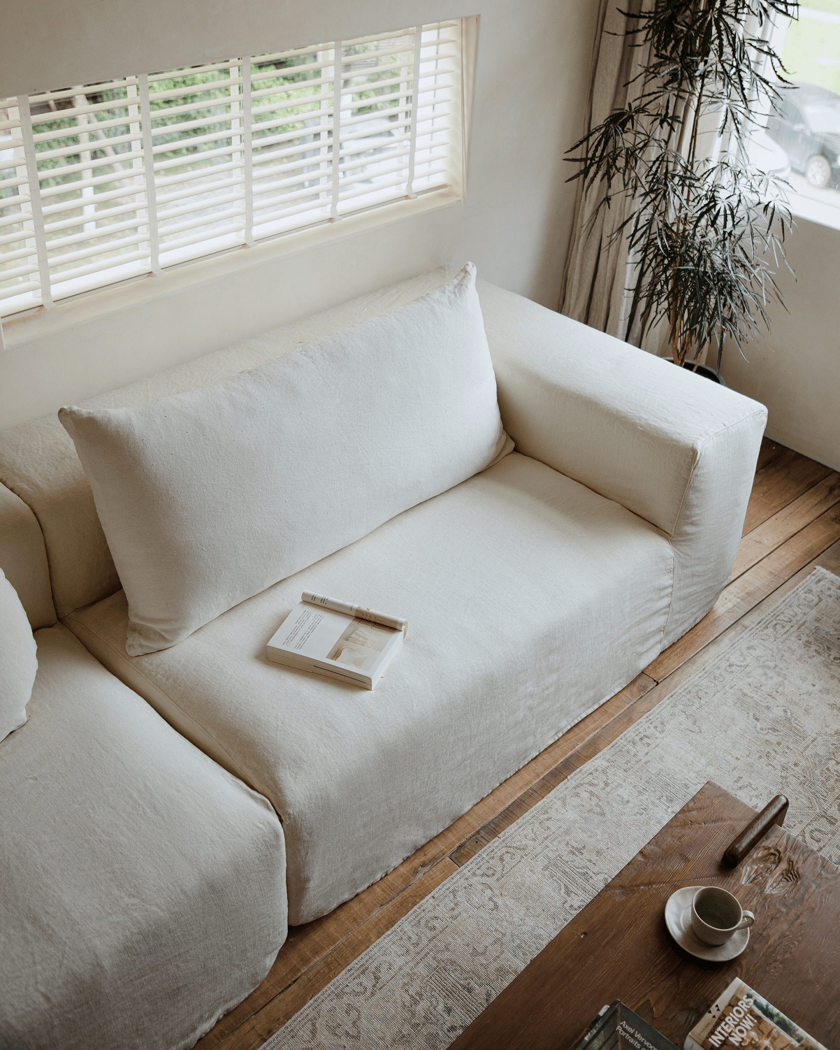 Doma Sectional Sofa in white linen with wide armrests in a bright, airy living space. Modular design.