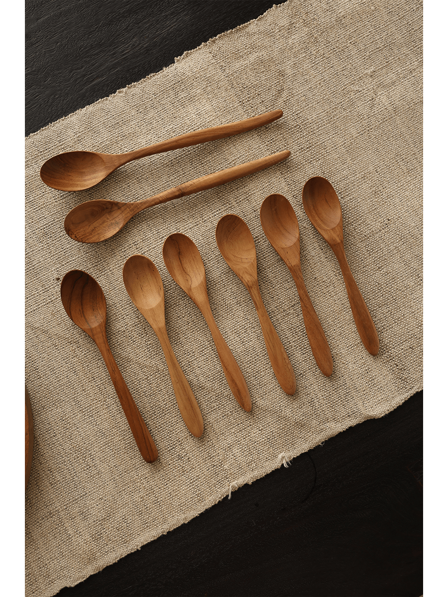 Set of wooden table spoons, natural wood finish, placed on a beige linen fabric, product shot.