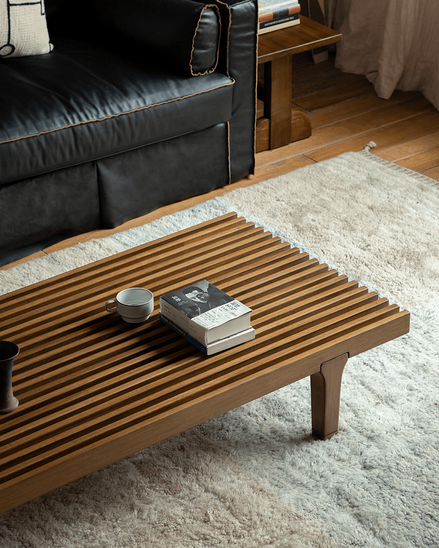 ZM Daybed Coffee Table in teak wood, minimalist design, with slatted top, books and a cup.