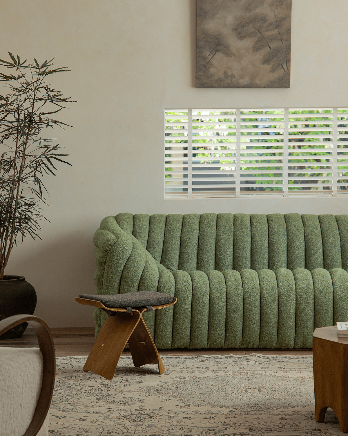 Butterfly Stool in a modern interior setting next to a green sofa, showing design and material.